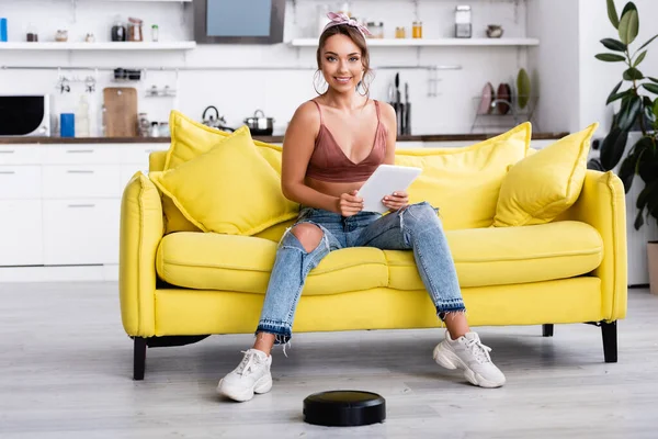 Femme assise et regardant la caméra près de l'aspirateur robotique — Photo de stock