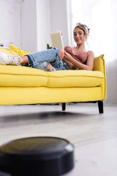 Selective focus of woman lying on couch and robotic vacuum cleaner — Stock Photo