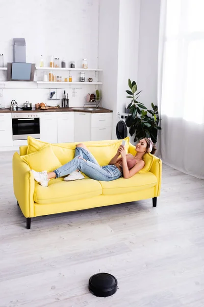 Frau liegt auf Couch und nutzt Smartphone — Stockfoto