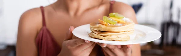 Panoramic orientation of woman holding tasty pancakes with fruits — Stock Photo
