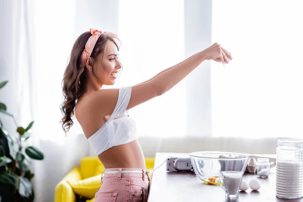Seitenansicht der Frau gießt Ei in Schüssel in der Nähe von Mehl in der Küche — Stockfoto