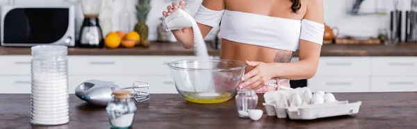 Concepto panorámico mujer mujer verter azúcar en la proa con huevos mientras cocina en casa - foto de stock