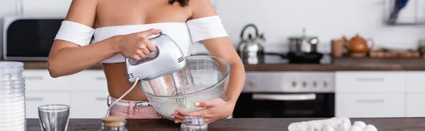 Site en-tête de femme au foyer mélangeant des ingrédients près des œufs et de la farine dans la cuisine — Photo de stock