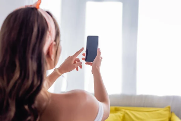 Concentration sélective de la jeune femme à l'aide d'un smartphone avec écran blanc à la maison — Photo de stock