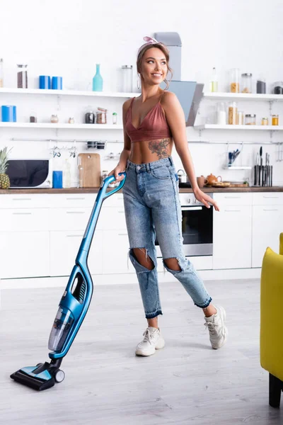 Вибірковий фокус сучасної домогосподарки прибирання підлоги за допомогою пилососа в домашніх умовах — стокове фото