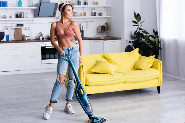 Housewife cleaning floor with modern vacuum cleaner at home — Stock Photo