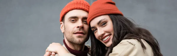 Panoramic crop of stylish couple in beanie hats looking at camera — Stock Photo