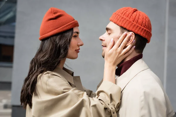 Vue latérale de la femme à la mode touchant l'homme en bonnet chapeau — Photo de stock