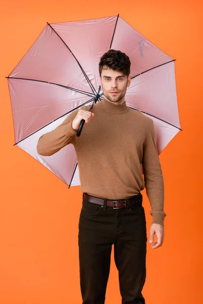 Elegante uomo in abito autunno in piedi sotto l'ombrello su arancione — Foto stock