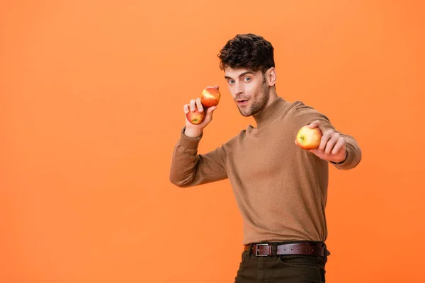 Homem em roupa de outono segurando maçãs frescas isoladas em laranja — Fotografia de Stock