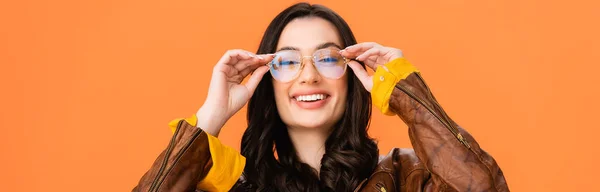 Plano panorámico de mujer elegante tocando gafas aisladas en naranja - foto de stock