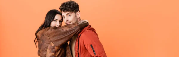 Horizontal crop of brunette woman hugging stylish man isolated on orange — Stock Photo