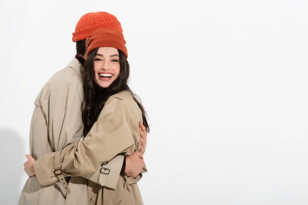 Donna alla moda in cappello beanie abbracciando l'uomo sul bianco — Foto stock