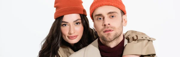 Orientação panorâmica do casal na moda em chapéus beanie olhando para a câmera isolada no branco — Fotografia de Stock