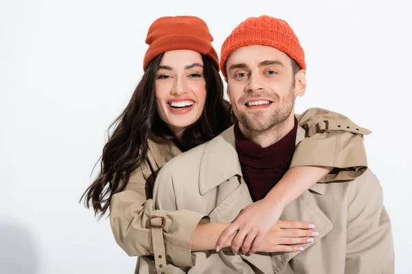 Gioiosa donna in cappello beanie abbracciando uomo alla moda su bianco — Foto stock