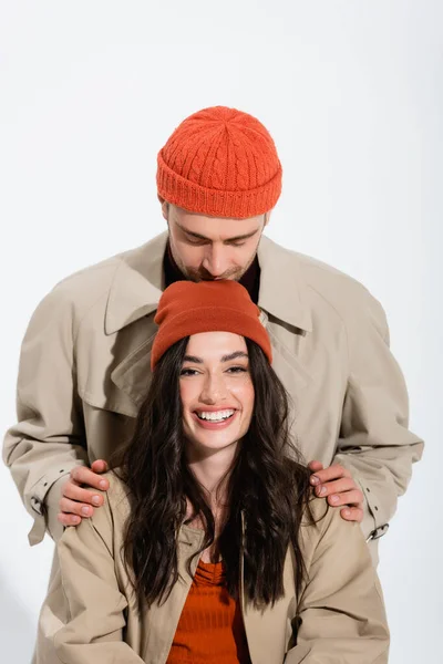 Homme en bonnet chapeau baisers tête de joyeuse femme isolé sur blanc — Photo de stock