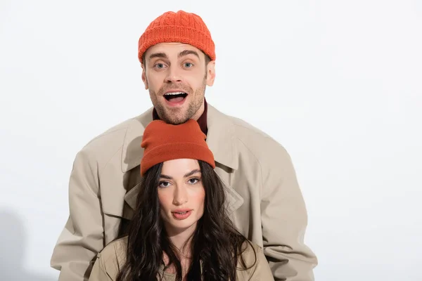 Excited man with open mouth near joyful woman in beanie hat on white — Stock Photo