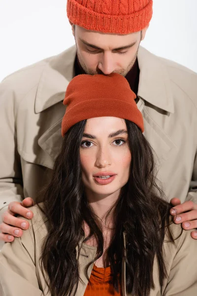 Homme en bonnet chapeau baisers tête de jeune femme isolé sur blanc — Photo de stock