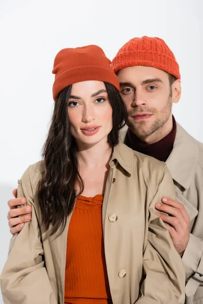 Hombre de moda en gorro sombrero tocando mujer joven con estilo en blanco - foto de stock