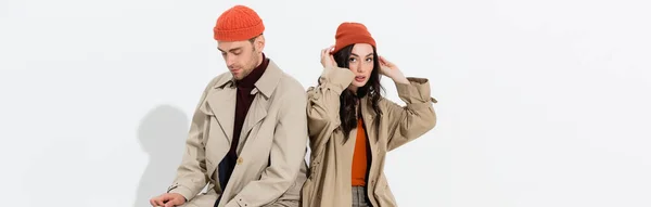 Заголовок веб-сайту жінки, що торкається капелюха бані біля модного чоловіка на білому — стокове фото
