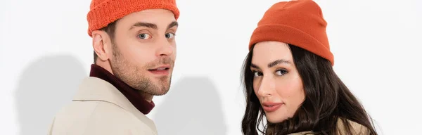Panoramic concept of trendy couple in beanie hats looking at camera on white — Stock Photo