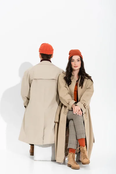 Back view of man sitting near young stylish woman in beanie hat on white — Stock Photo