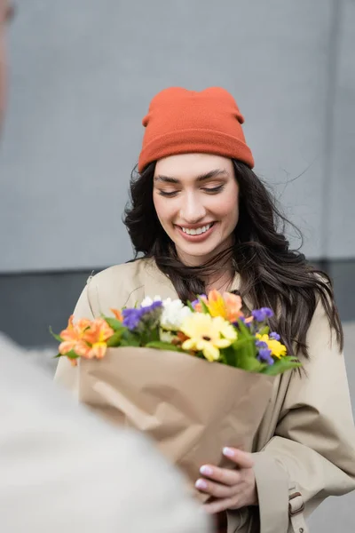 Selektiver Fokus der jungen Frau beim Betrachten eines Blumenstraußes — Stockfoto