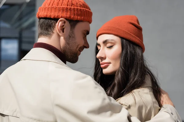 Couple à la mode avec les yeux fermés dans des trench-coats et des chapeaux — Photo de stock