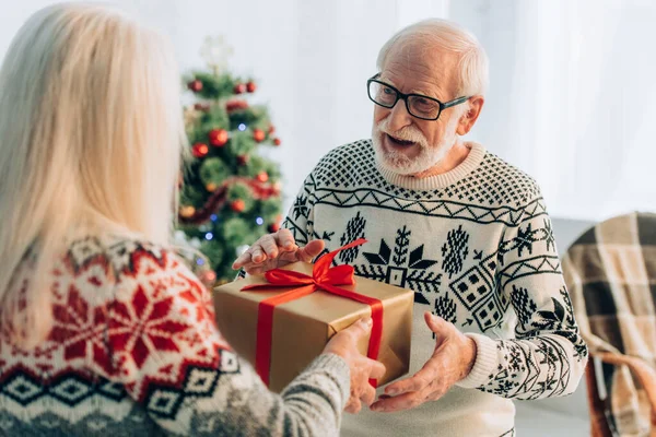 Vista posteriore della donna anziana che presenta la scatola regalo al marito felice — Foto stock