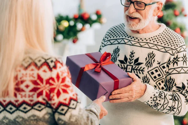 Enfoque selectivo del hombre mayor que presenta la caja de regalo a la esposa - foto de stock