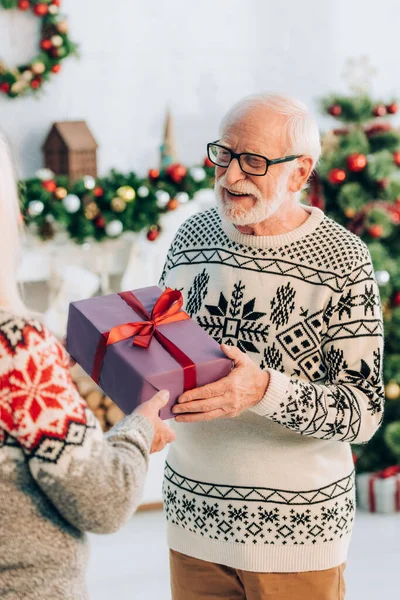 Selektiver Fokus des fröhlichen Seniors, der Geschenkbox von Frau nimmt — Stockfoto