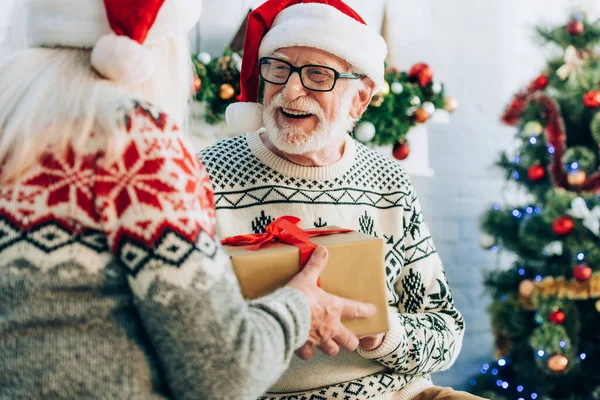 Messa a fuoco selettiva della donna anziana che presenta scatola regalo al marito allegro — Foto stock