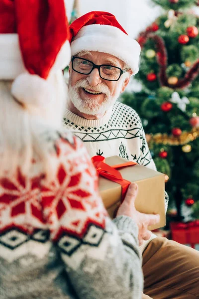 Back view of woman presenting gift box to happy senior husband — Stock Photo