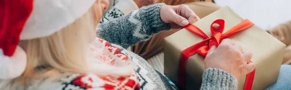 Zugeschnittene Ansicht einer Seniorin, die Weihnachtsgeschenkschachtel öffnet, Website-Header — Stockfoto