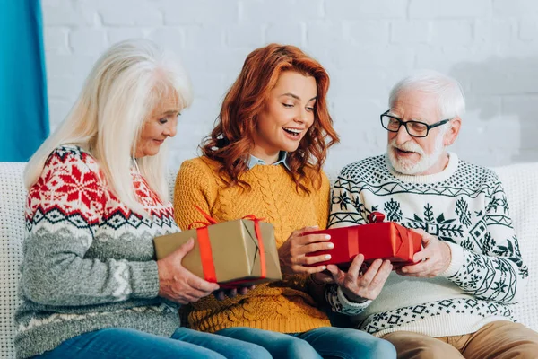 Excited woman taking christmas gifts from happy senior parents — Stock Photo