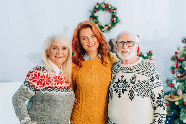 Heureux parents aînés avec fille regardant caméra dans la chambre avec décoration de Noël — Photo de stock