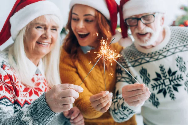Selective focus of senior couple with daughter lighting sparklers on christmas — Stock Photo