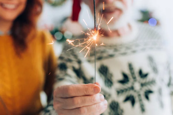 Selective focus of senior man holding sparkler near daughter — Stock Photo