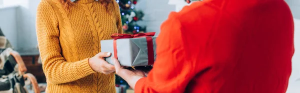 Foco seletivo do homem apresentando presente de Natal à esposa, tiro panorâmico — Fotografia de Stock