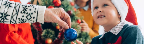 Panoramic shot of grandfather giving christmas ball to happy grandson — Stock Photo