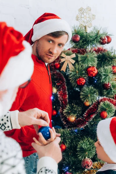 Enfoque selectivo del hombre mayor dando bola de Navidad al nieto cerca del padre - foto de stock