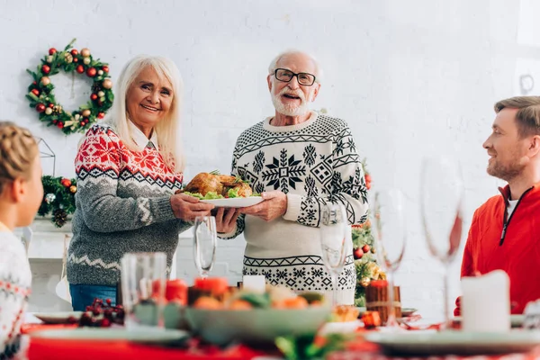 Selektiver Fokus älterer Menschen mit Truthahn in der Nähe von Familie und Festtafel — Stockfoto