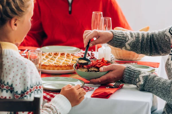 Selective focus of woman holding bowl and serving vegetable on plate near girl — Stock Photo