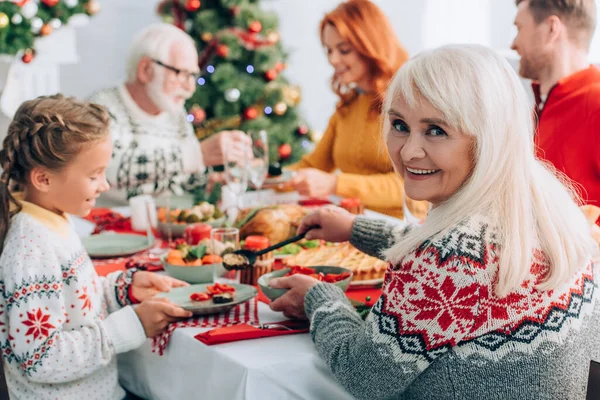 Selektiver Fokus der Großmutter, die Gemüse serviert und zu Hause in die Kamera schaut — Stockfoto