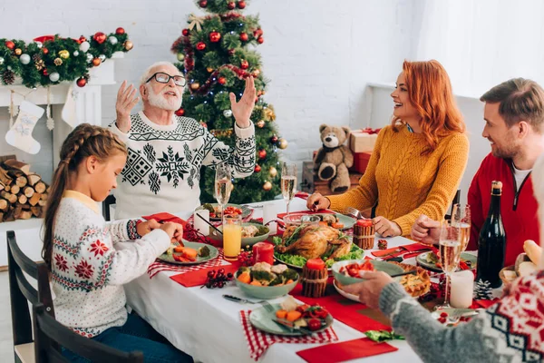 Famille assise à table festive avec dîner d'action de grâces près de la cheminée à la maison — Photo de stock