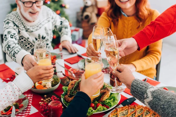 Enfoque selectivo del brindis familiar feliz mientras se sienta en la mesa festiva en casa - foto de stock