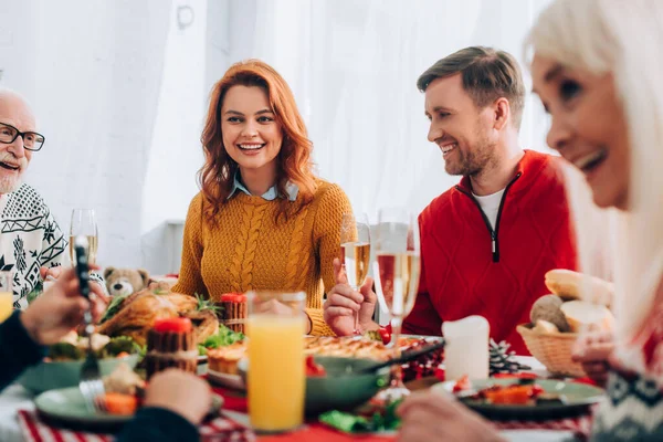 Foco seletivo de mulher feliz e homem, sentado na mesa festiva com a família — Fotografia de Stock