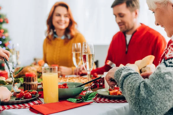 Focus selettivo della nonna sorridente che mangia, seduta al tavolo festivo con la famiglia — Foto stock