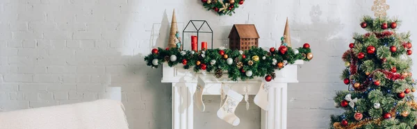 Panoramic shot of fireside with christmas stockings and decorated pine — Stock Photo