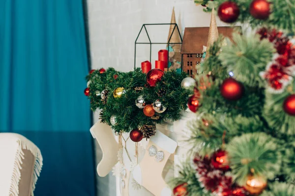 Decorated pine branches with baubles and candles near fireplace — Stock Photo